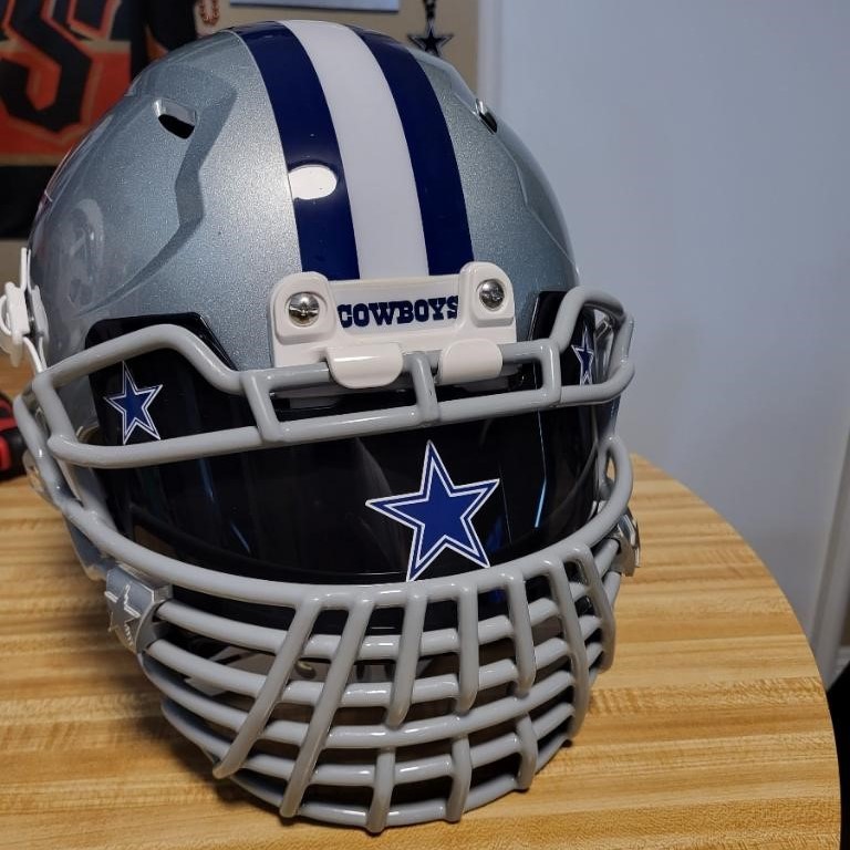 A Dallas Cowboys helmet with a tinted visor and a grate facemask.